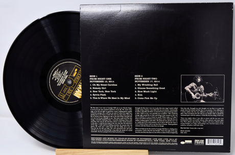 Vinyl record with cover displaying text and a photo of a person playing guitar.