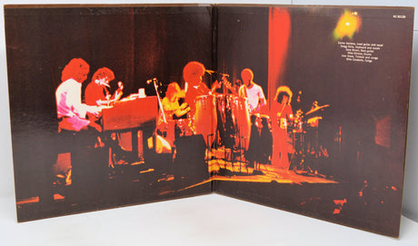 An open vinyl record sleeve or album booklet showing a live band performance printed on the inside cover, photographed against a plain light background.