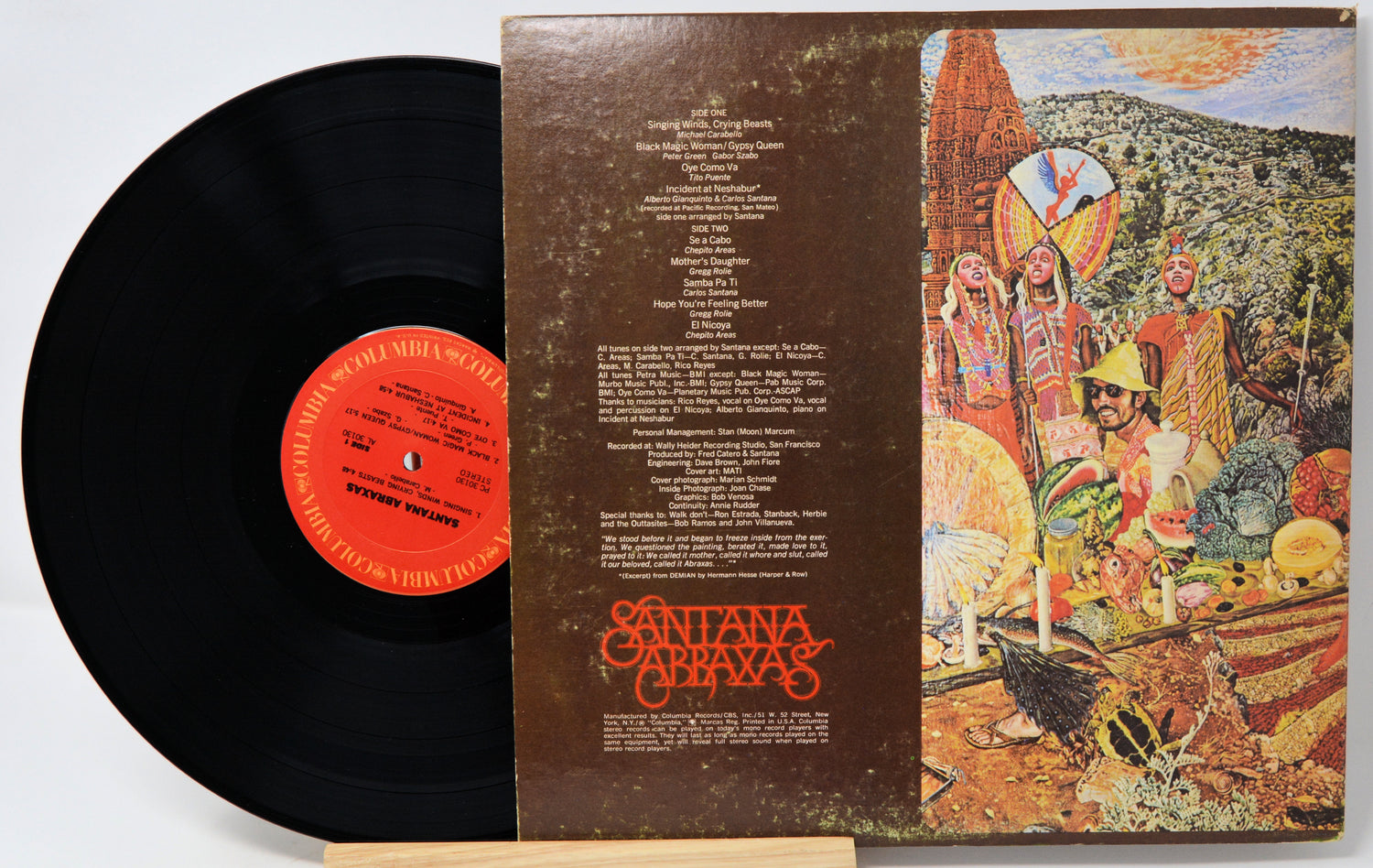 A vintage Santana 'Chivas' vinyl record shown open, with the black record partially visible on the left and the illustrated album cover on the right. The center label is orange-red, and the cover features a colorful desert scene with the Santana Chivas logo in orange at the bottom.