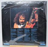Vinyl record album back cover under shrink wrap, featuring a black background with a large portrait of a guitarist and track listing text below.