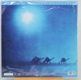 A vinyl record sleeve  'Original Master Recordings' featuring a blue-toned desert scene with camels and a bright sun, photographed in clear plastic wrapping.