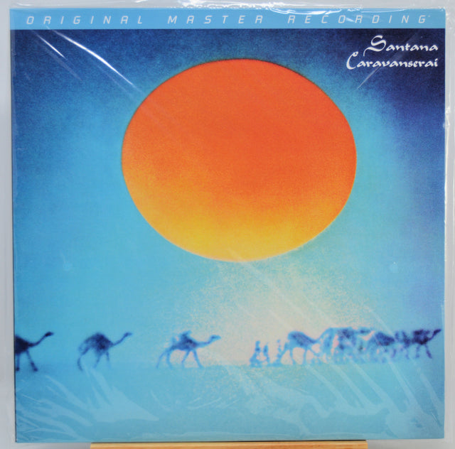 Santana's 'Caravana' original master recording vinyl LP cover, sealed in plastic shrink wrap. The cover art features a large orange sun against a blue sky with silhouettes of camels and people walking across a desert landscape.