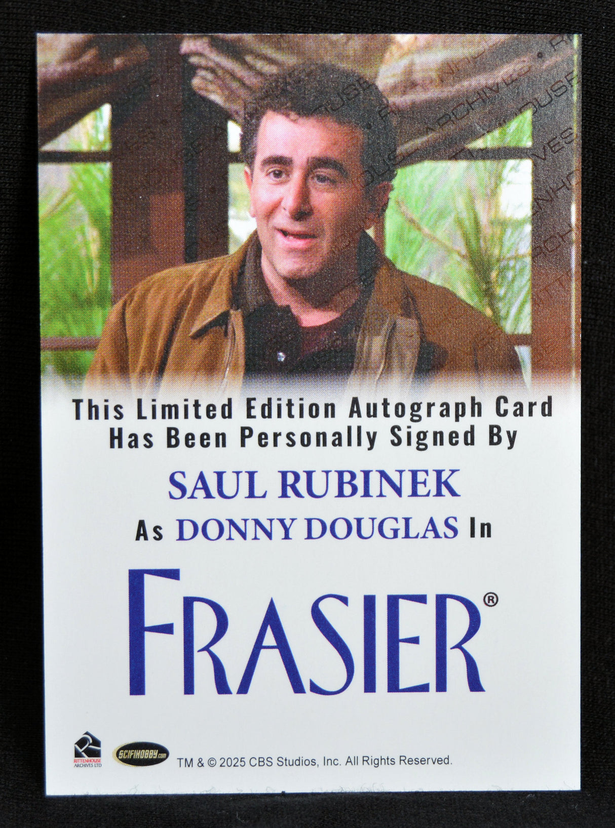Autograph card of Saul Rubinek as Donny Douglas in Frasier with a signature on a scenic background.