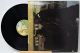 Vinyl record with a black cover featuring a house and trees, on a white background.