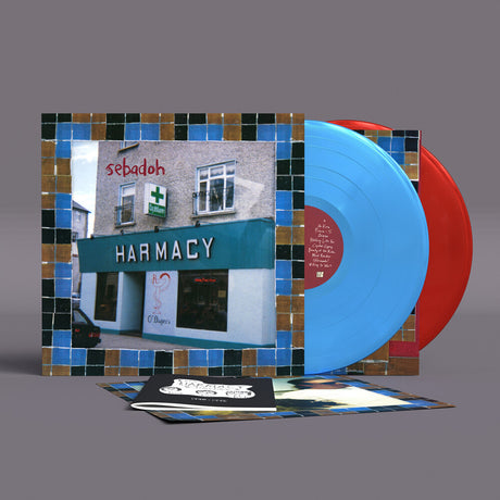 A vinyl record album set displayed on a gray background, featuring a square illustrated cover with a pharmacy storefront scene and blue mosaic tile borders, a bright blue record, a red record, and printed inserts in front.