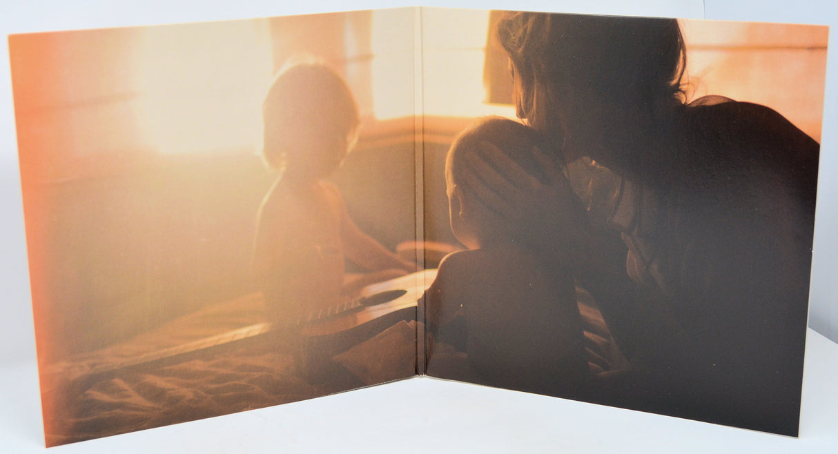 Open book showing a silhouette of a person and child against a sunset sky.