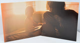 Open book showing a silhouette of a person and child against a sunset sky.