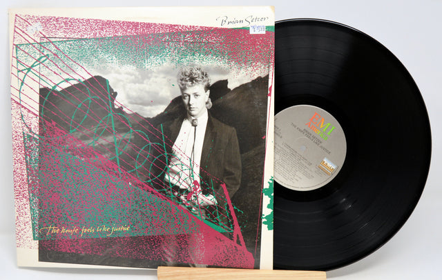 A used vinyl record titled 'The Knife Feels Like Justice' by Brian Setzer, with the album cover placed next to it.