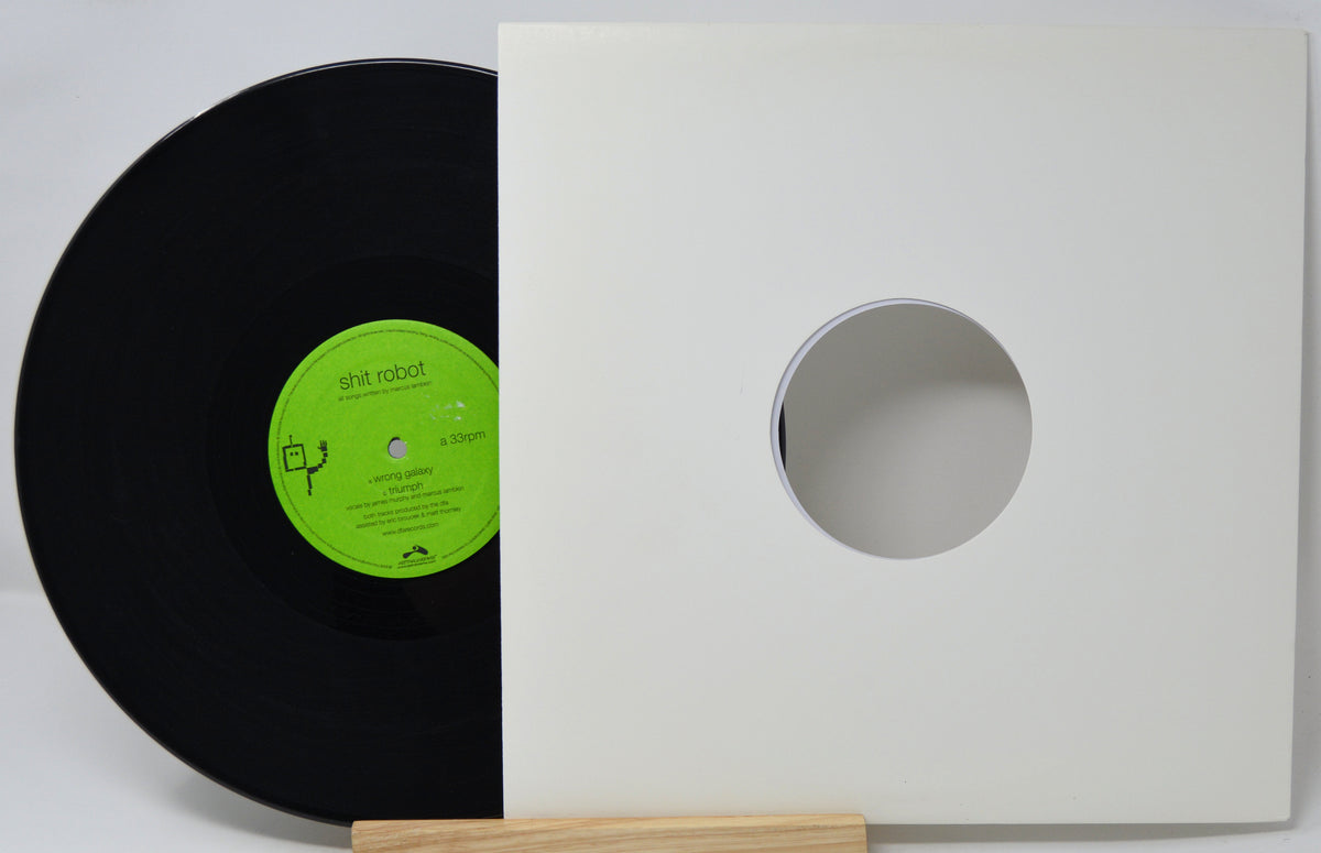 A black vinyl record with a bright green label partially tucked behind a white square sleeve or insert with a circular cutout, photographed on a light background with a small wooden stand visible at the bottom.