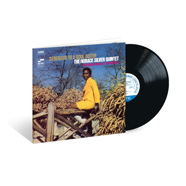 A vinyl record of Horace Silver's album 'Serenade To A Soul Sister' with the artist seated on a wooden structure in a natural setting, smiling, with the album cover in a blue and white color scheme.