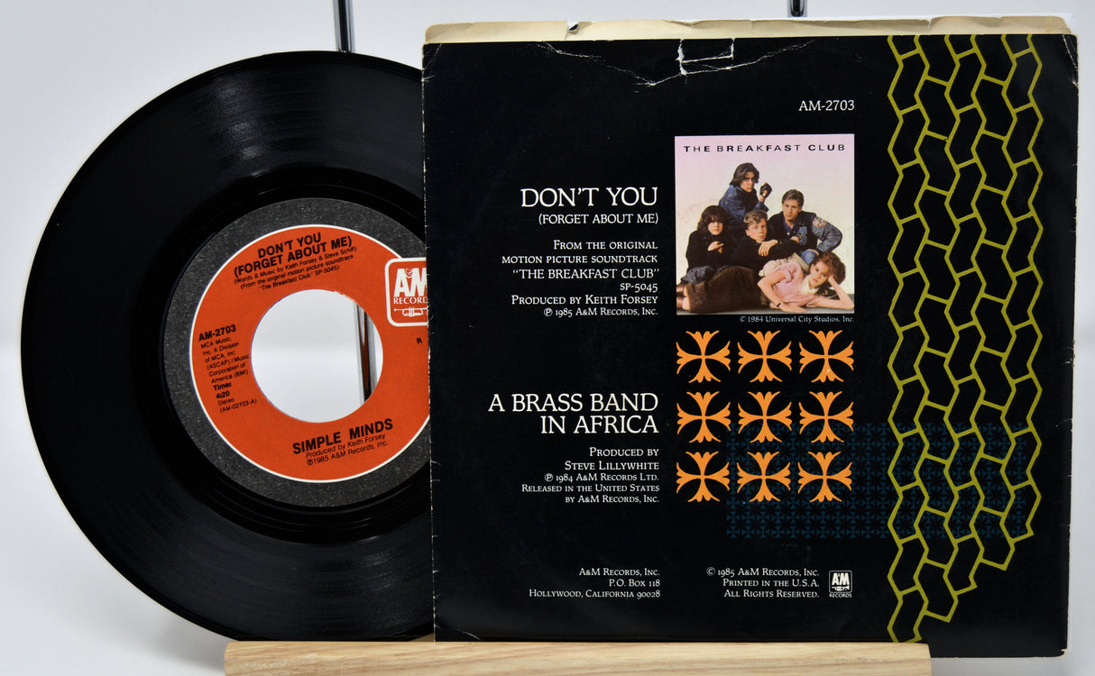 Vinyl record and its cover with 'Don't You (Forget About Me)' by Simple Minds on a white background