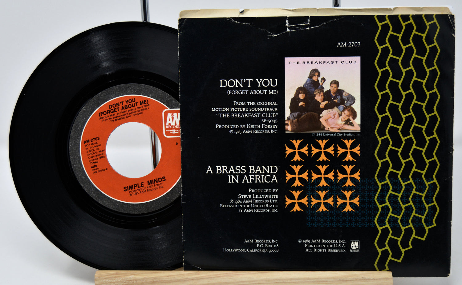 Vinyl record and its cover with 'Don't You (Forget About Me)' by Simple Minds on a white background