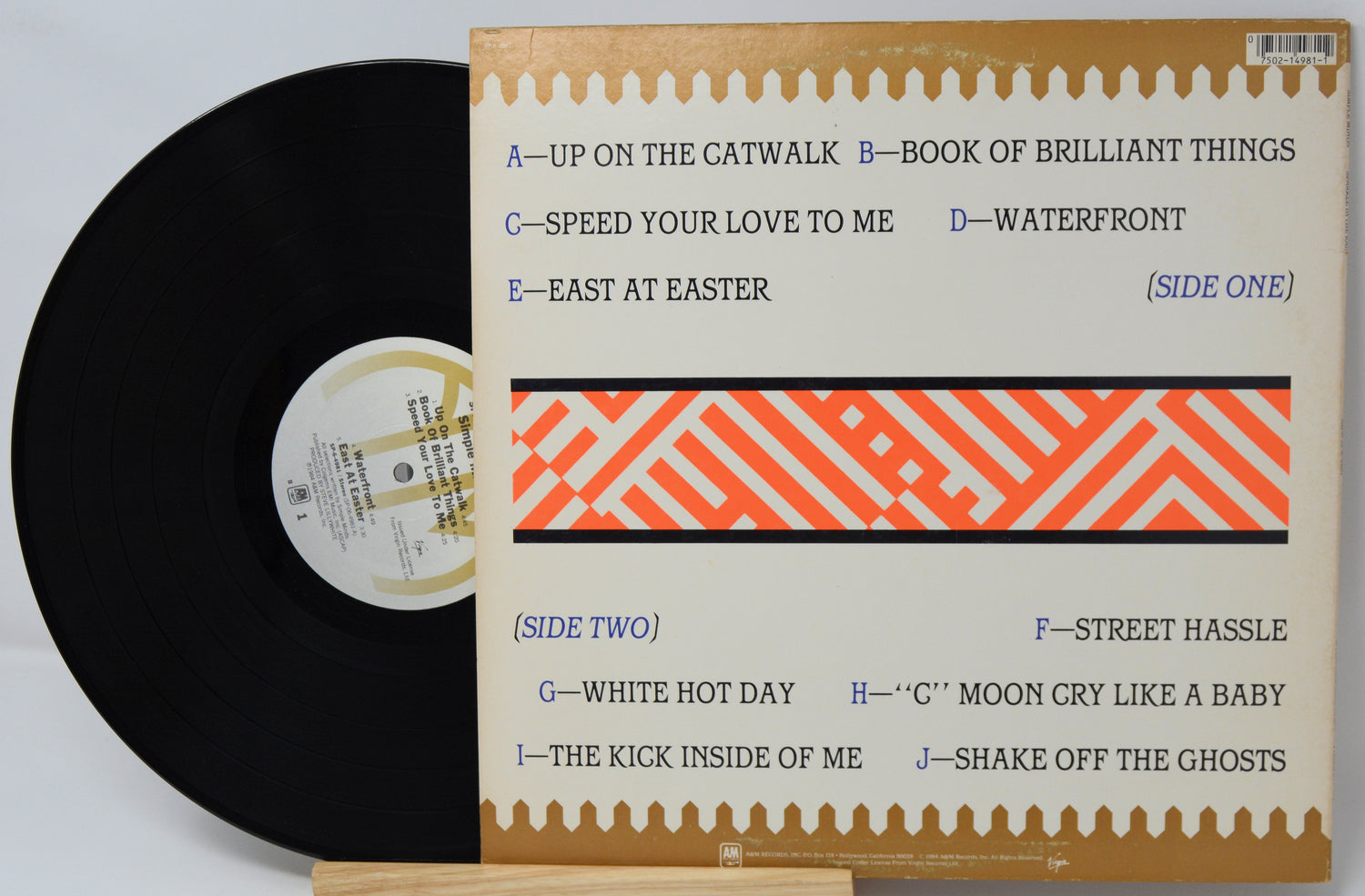 Vinyl record with cover displaying track listings on a light gray background