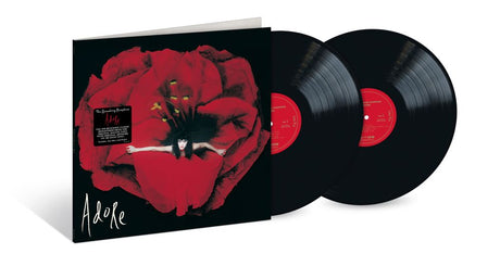 A vinyl record album shown with its illustrated outer sleeve and two black records partially pulled out. The sleeve features a large red flower and the word 'Adore' in white script.