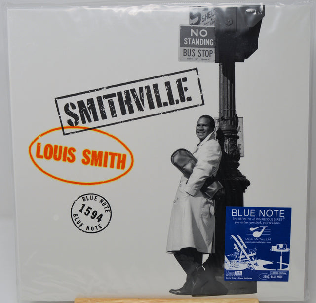 Louis Smith's 'Smithville' Blue Note vinyl record album, still sealed in its original plastic shrink wrap. The cover features a black and white photograph of a man leaning against a street lamp, with a blue 'Blue Note' sticker in the bottom right corner.