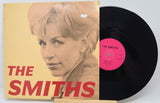 Vinyl record with 'The Smiths' album cover featuring a portrait of a woman.
