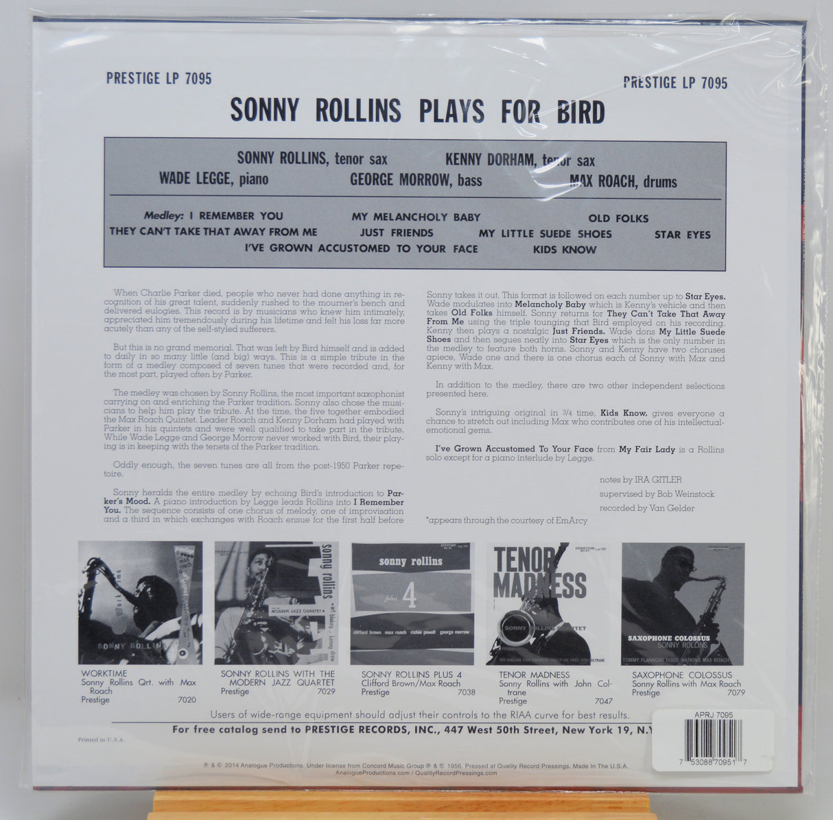 The back cover of a vinyl record sleeve for Prestige LP 7095, featuring Sonny Rollins playing for bird, photographed inside a clear plastic protective sleeve. The cover has a white background with black text, a central gray band listing band members, and several small black-and-white photos at the bottom.