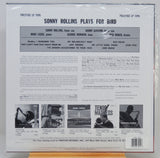 The back cover of a vinyl record sleeve for Prestige LP 7095, featuring Sonny Rollins playing for bird, photographed inside a clear plastic protective sleeve. The cover has a white background with black text, a central gray band listing band members, and several small black-and-white photos at the bottom.