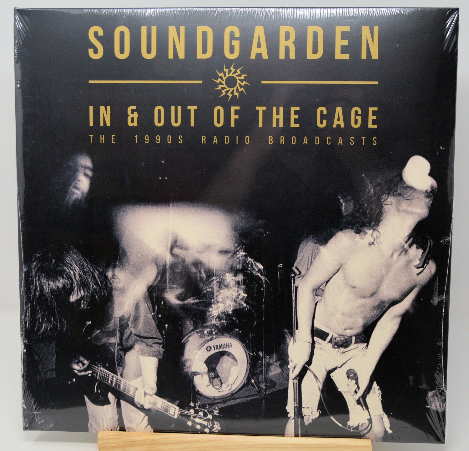 Soundgarden 'In & Out of the Cage: The 1990s Radio Broadcasts' vinyl record cover, shrink-wrapped and displayed upright on a small wooden stand against a light gray background.