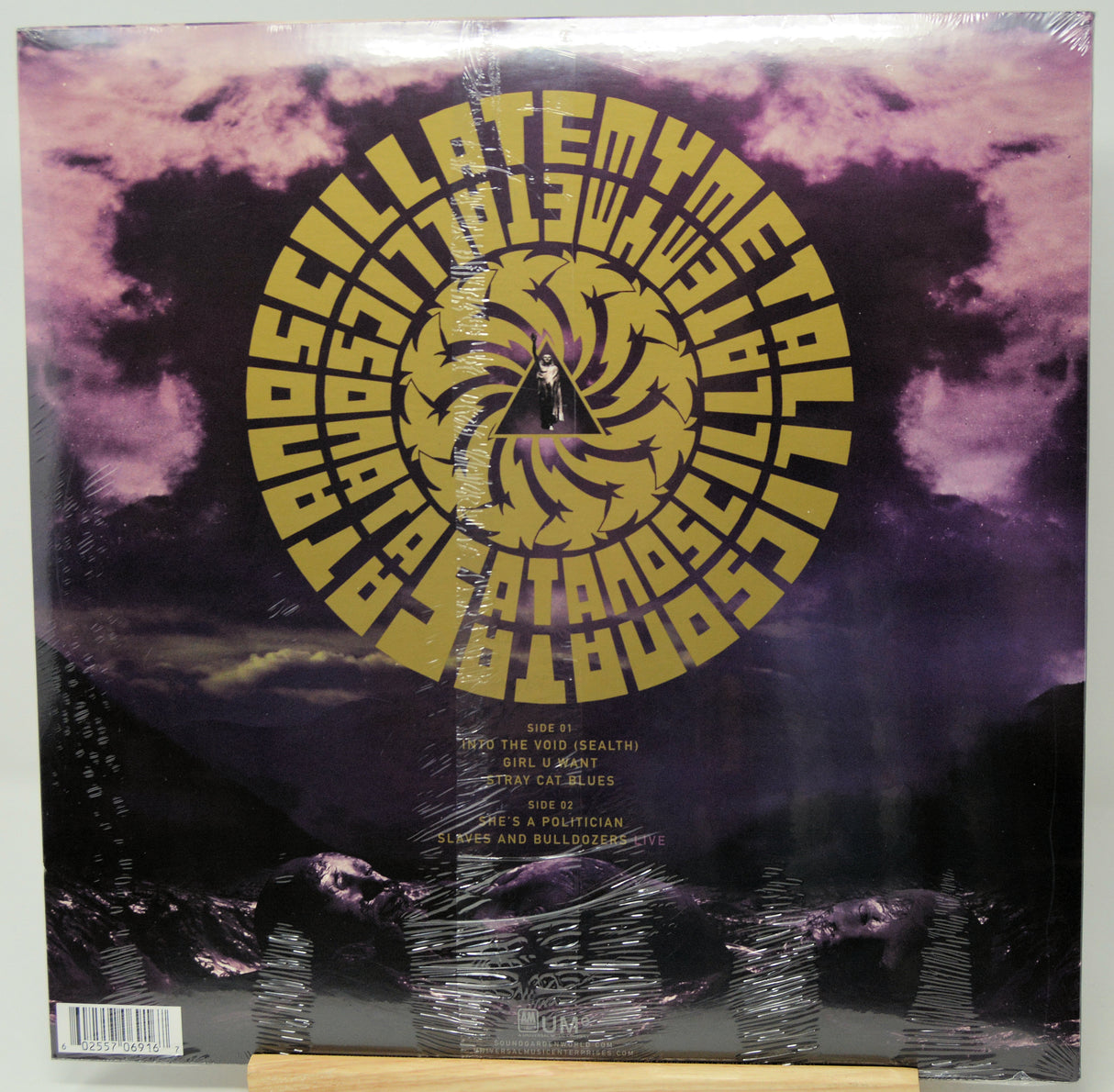 A vinyl record sleeve for 'Asylum' by the band Death Cab for Cutler, featuring a large gold spiral logo over a purple and black stormy sky background. The record is still sealed in its plastic shrink wrap and is photographed flat.