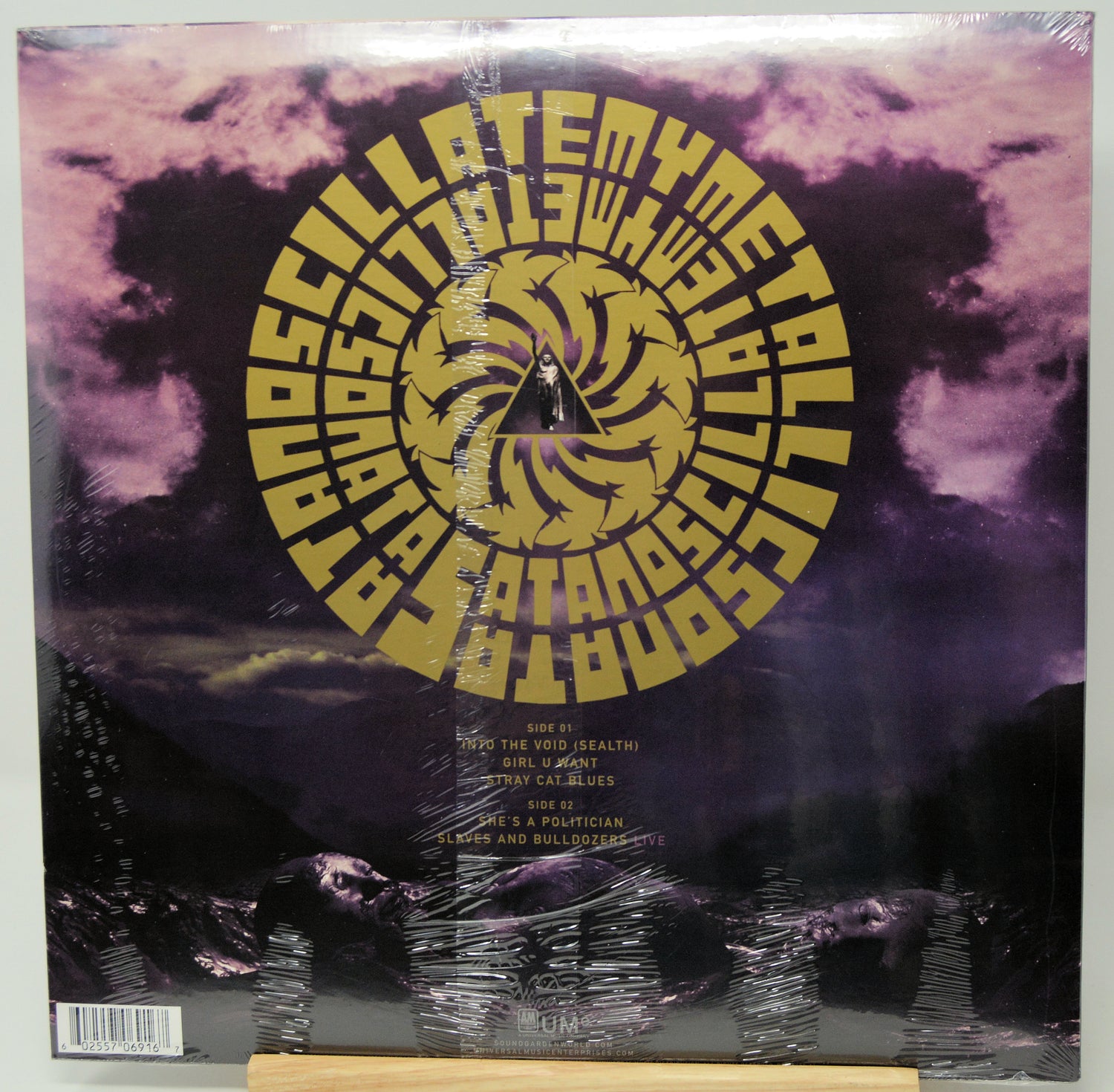 A vinyl record sleeve for 'Asylum' by the band Death Cab for Cutler, featuring a large gold spiral logo over a purple and black stormy sky background. The record is still sealed in its plastic shrink wrap and is photographed flat.