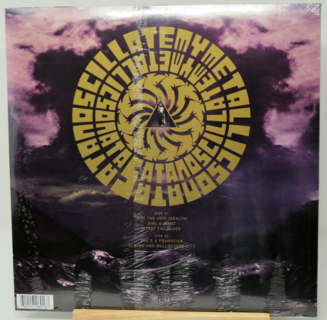A vinyl record sleeve for 'Asylum' by the band Death Cab for Cutler, featuring a large gold spiral logo over a purple and black stormy sky background. The record is still sealed in its plastic shrink wrap and is photographed flat.