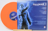 Vinyl record with orange disc and blue cover featuring a silhouette of a character holding a knife, on a white background.