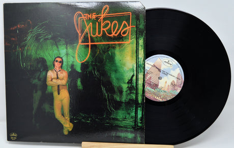 Vinyl record with cover featuring a person in a suit and green abstract design, on a white background.
