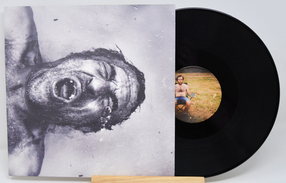 Vinyl record with a cover featuring a black and white image of a person and a circular cutout showing a person in a field.