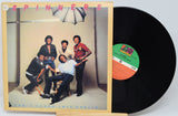 Vinyl record with cover featuring a group of people and album details.