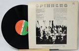 Vinyl record with cover featuring a group of people and text, on a light gray background.