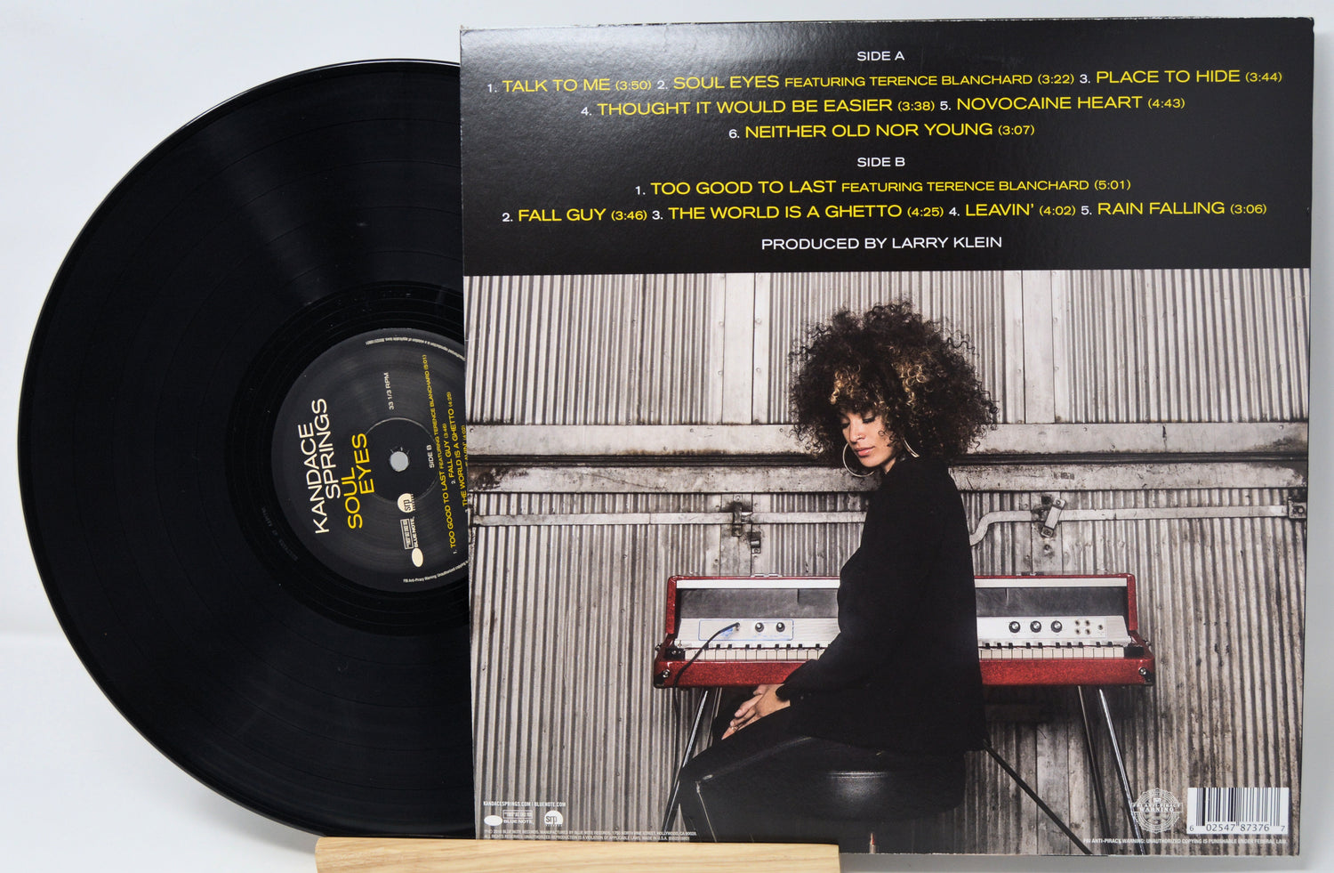 Vinyl record with a cover featuring a person playing an keyboard, on a light gray background.