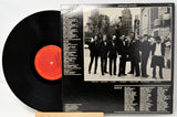 Vinyl record with cover featuring a black and white photo of a group of people in suits.