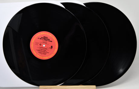 Three black vinyl records with a red label on a white background