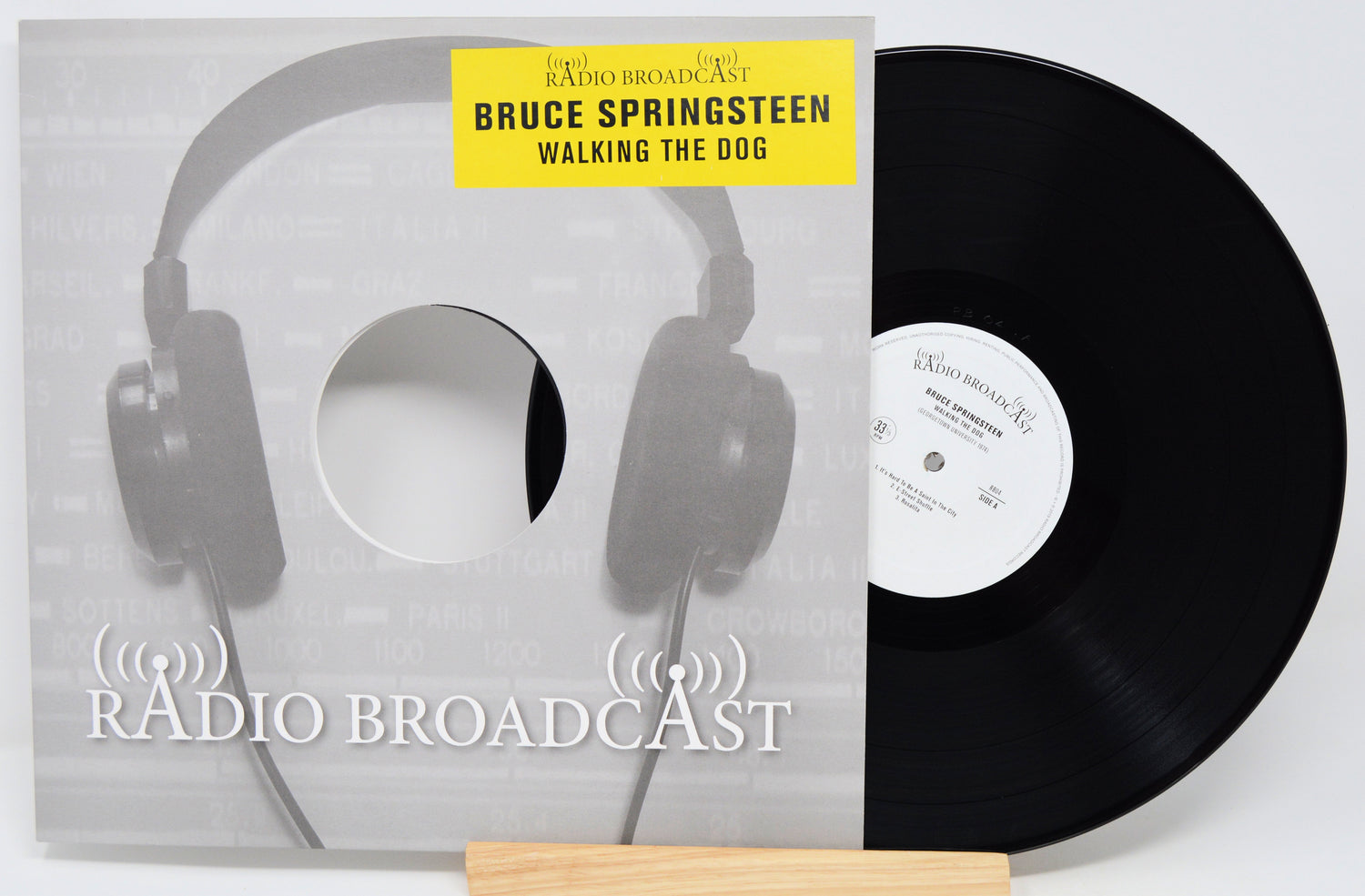 Vinyl record with cover featuring headphones and 'Radio Broadcast' text, displaying Bruce Springsteen's album 'Walking the Dog'.