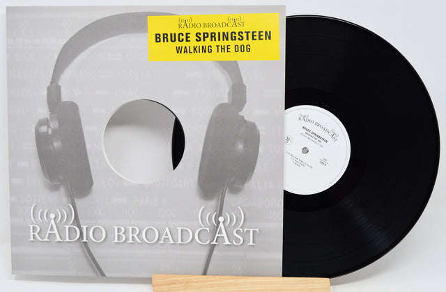 Vinyl record with cover featuring headphones and 'Radio Broadcast' text, displaying Bruce Springsteen's album 'Walking the Dog'.
