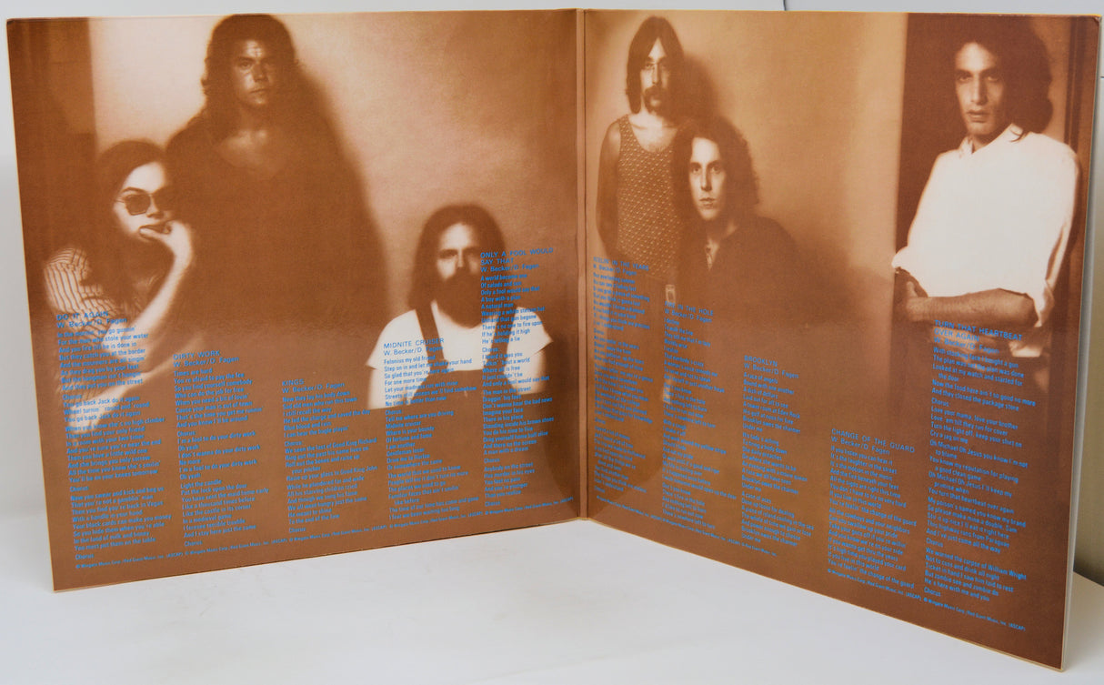 An open vinyl record sleeve or booklet showing sepia-toned band portraits and dense blue text printed across both pages, photographed on a white surface.