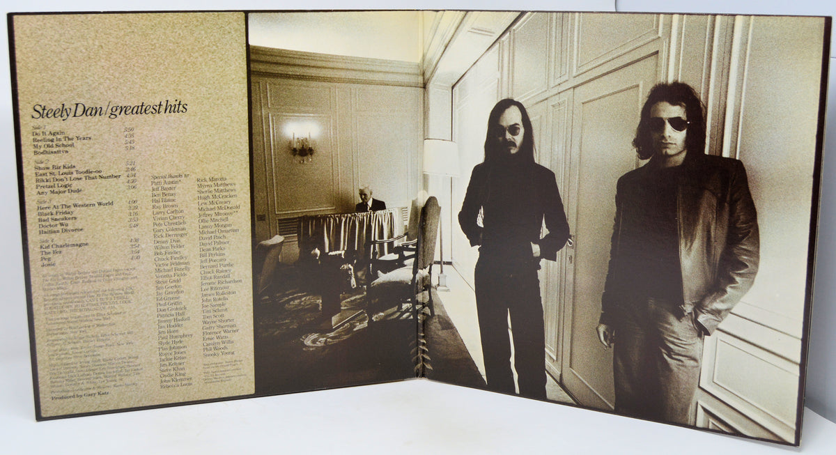 A vinyl record sleeve or album booklet shown open, featuring a sepia-toned tracklist on the left panel and a black-and-white interior photograph of a man in a room on the right. The title 'Steely Dan / greatest hits' is visible at the top left.