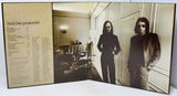 A vinyl record sleeve or album booklet shown open, featuring a sepia-toned tracklist on the left panel and a black-and-white interior photograph of a man in a room on the right. The title 'Steely Dan / greatest hits' is visible at the top left.