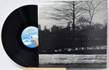 Vinyl record with a black and white cover featuring a tree and skyline.