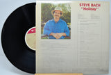 Vinyl record with cover featuring a man in a blue shirt and hat, titled 'Holiday' by Steve Bach.