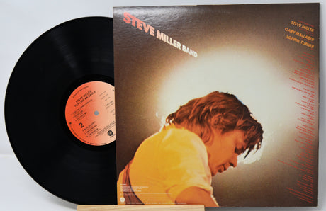 Vinyl record with cover featuring a person in a yellow shirt on a gray background