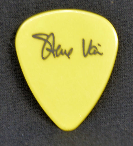 Yellow guitar pick with Steve  Vai signature on a black background