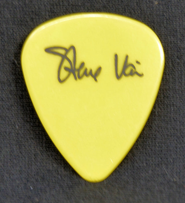 Yellow guitar pick with Steve  Vai signature on a black background