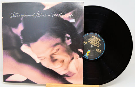 Steve Winwood's 'Back in the High Life' vinyl record album, showing the illustrated cover sleeve on the left and the black LP record partially pulled out on the right.