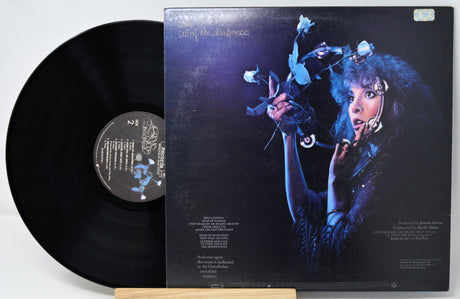 Vinyl record with its cover featuring a person holding flowers against a dark background.