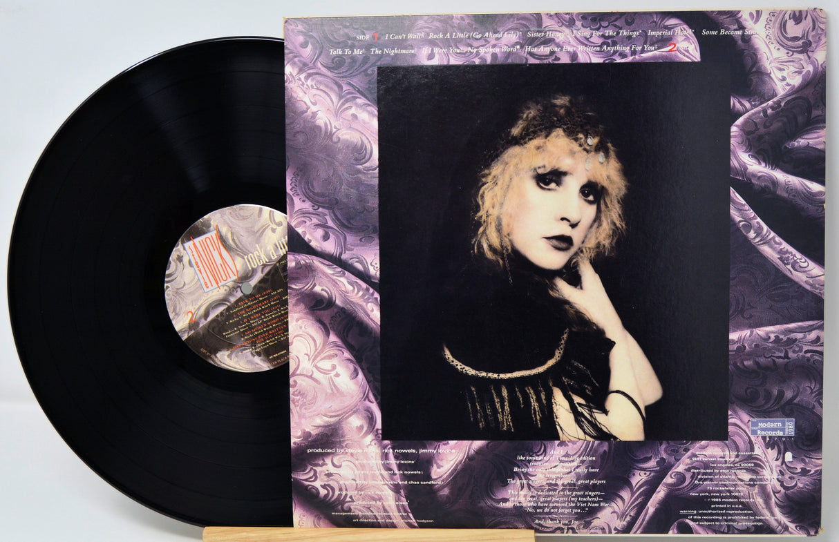Vinyl record with a stylized cover featuring a person's portrait and decorative elements.