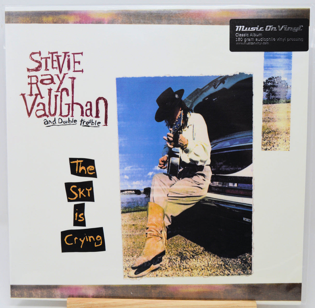 Vinyl record album cover for Stevie Ray Vaughan and Double Franklind's 'The Skies Are Crying' on Music On Vinyl, featuring a central photo of the musician sitting on the back of a car and stylized text on a white background.