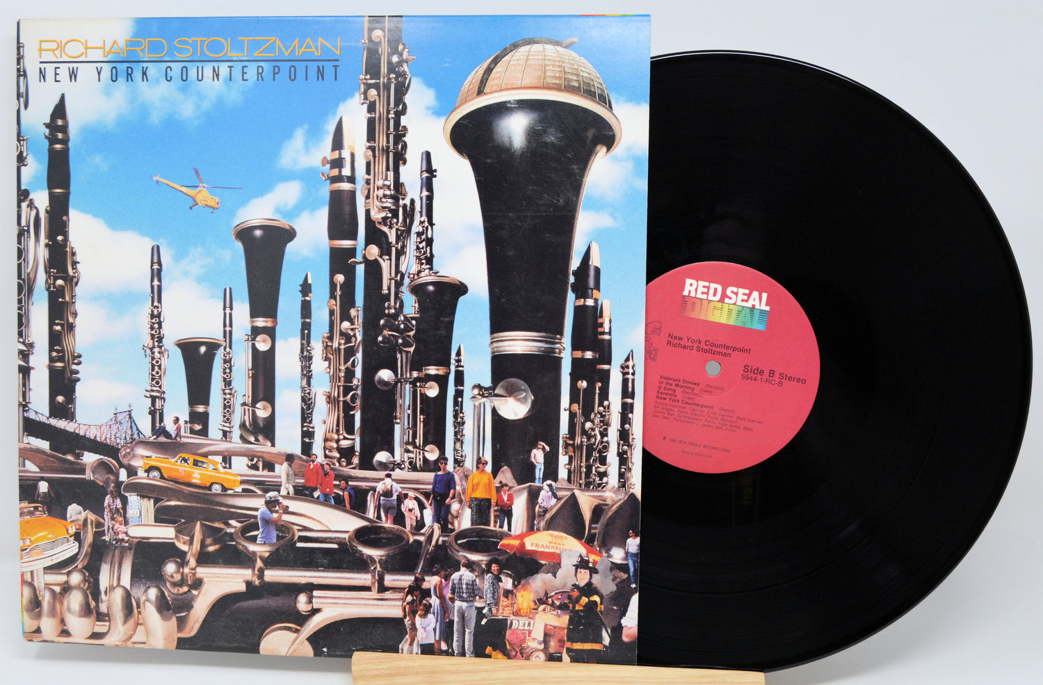 Vinyl record with a futuristic album cover featuring tall buildings and a helicopter.