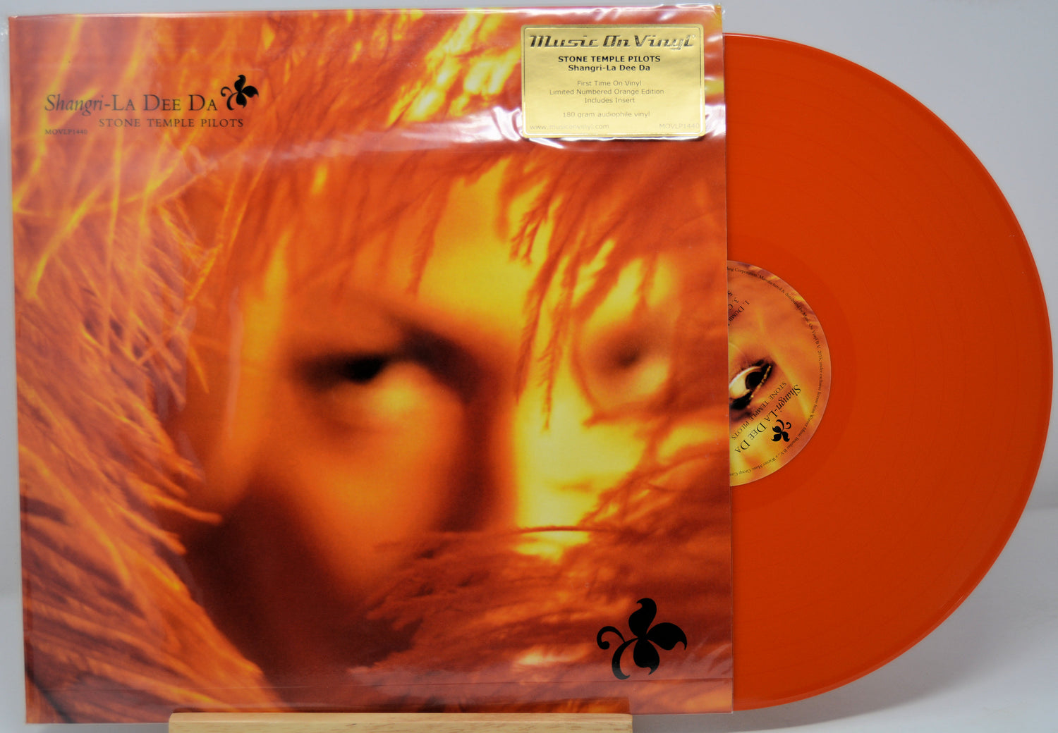 Orange vinyl record with a face on the cover and a visible label.